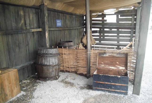 Wooden structure, open to the weather, with a barrel and chest for storing goods