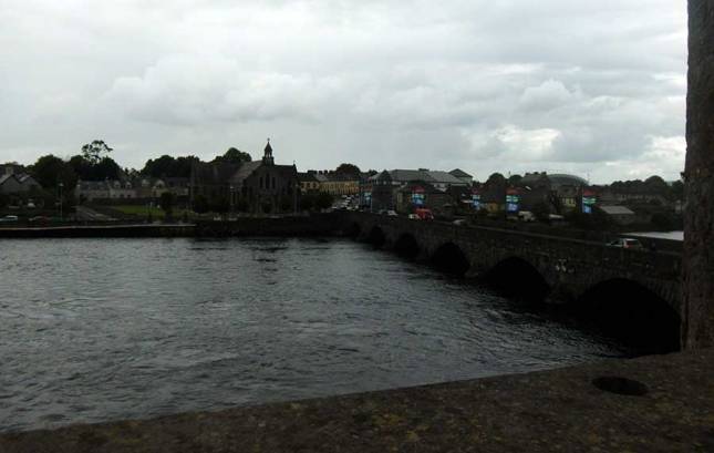 View of the wide Shannon River with a stone bridge to the right.