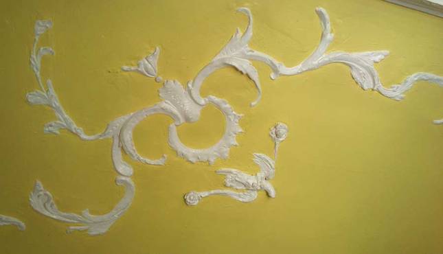 White plaster designs on the yellow ceiling.