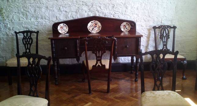 A sideboard with chair and decorated plates in the drawing room.
