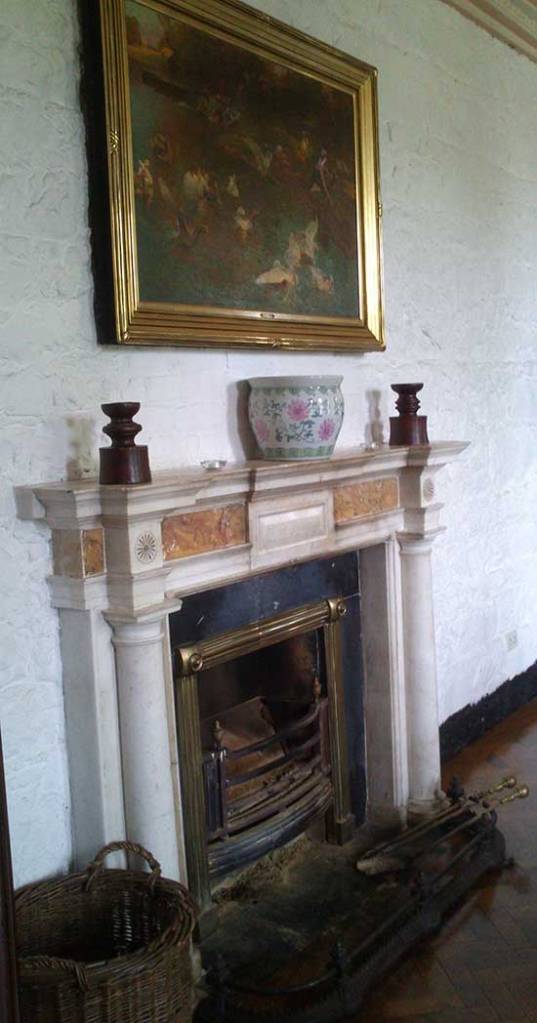 Another ornate fireplace with large painting above in the dining room.