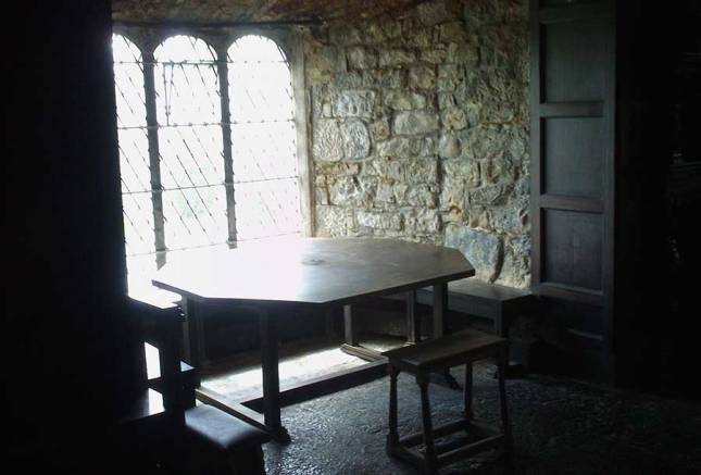 A octagonal table with chairs located in a large window.