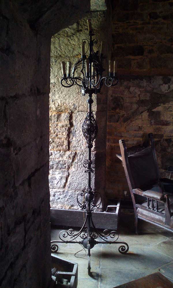 An approximately six-foot tall iron candlestick with three tiers of candles.